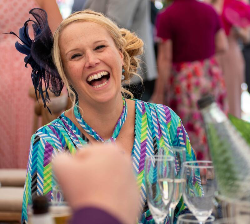 A race goer laughing at a hospitality table.