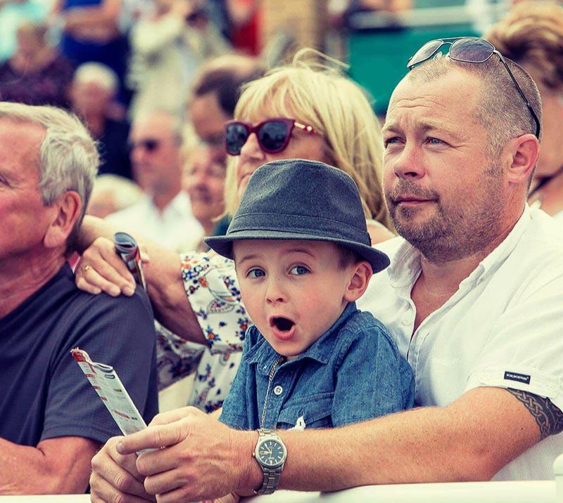 A young lad gives a cheeky eye to the camera from the safety of his Dads arms