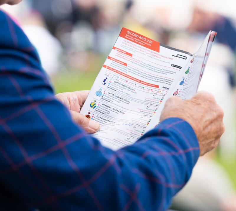 A close up of a race card over the shoulder of a race goer at Great Yarmouth Racecourse