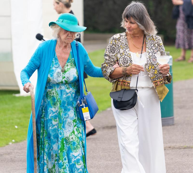 Two ladies at Great Yarmouth races make their way slowly across the enclosure with their drinks