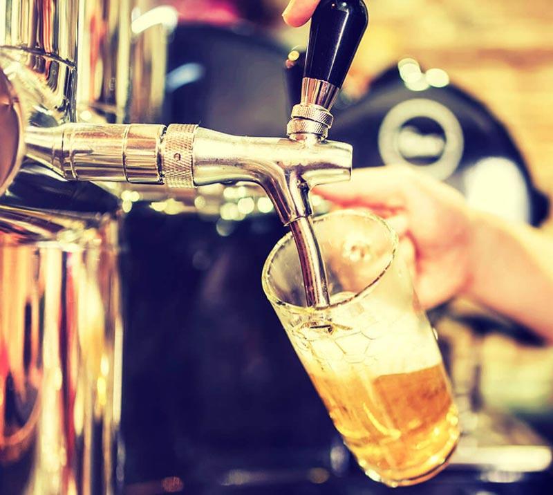 Bar waiter pouring a glass of beer from a tap.
