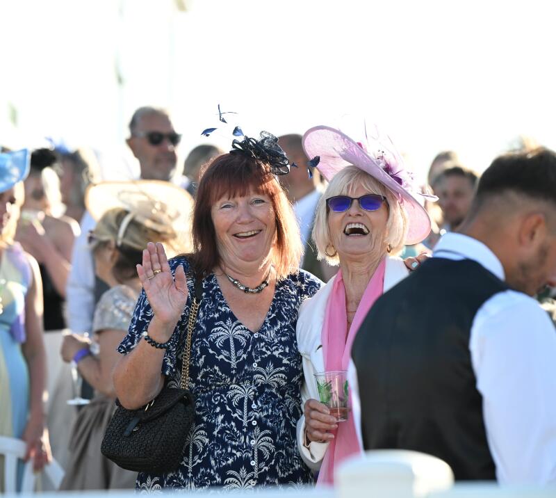 Two ladies in the crowd laugh as they have their photo taken at Great Yarmouth Races