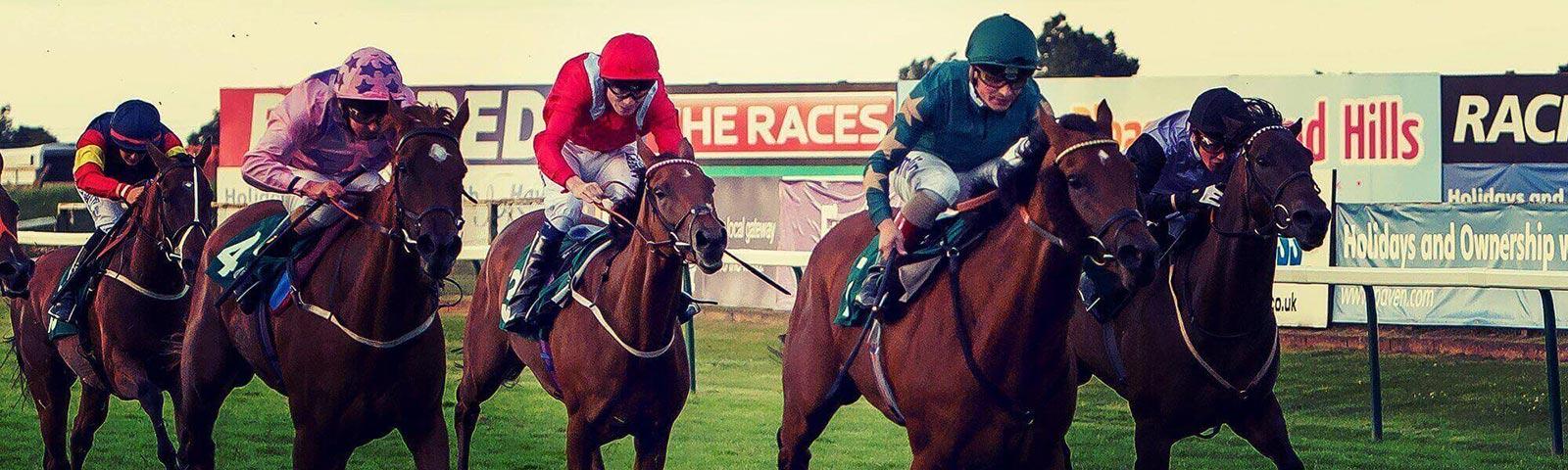 A group of horses run past promotional boarding.