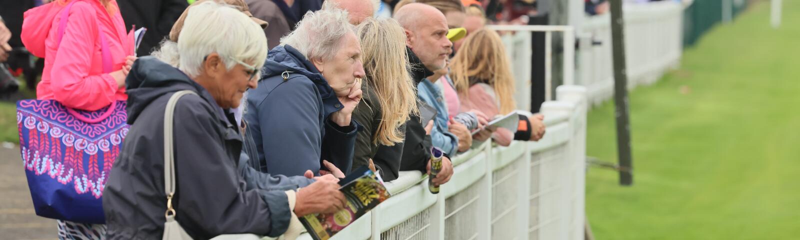Racegoers line the track at Great Yarmouth, some holding race cards