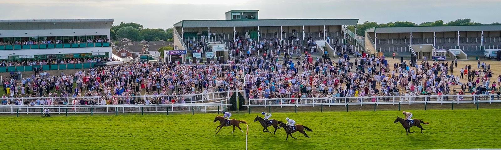 Group of jockeys racing past the grandstand at Great Yarmouth Racecourse.